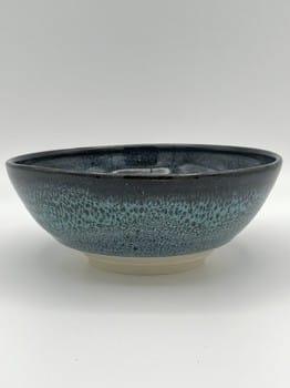 Ceramic bowl with blue speckled glaze on a white background