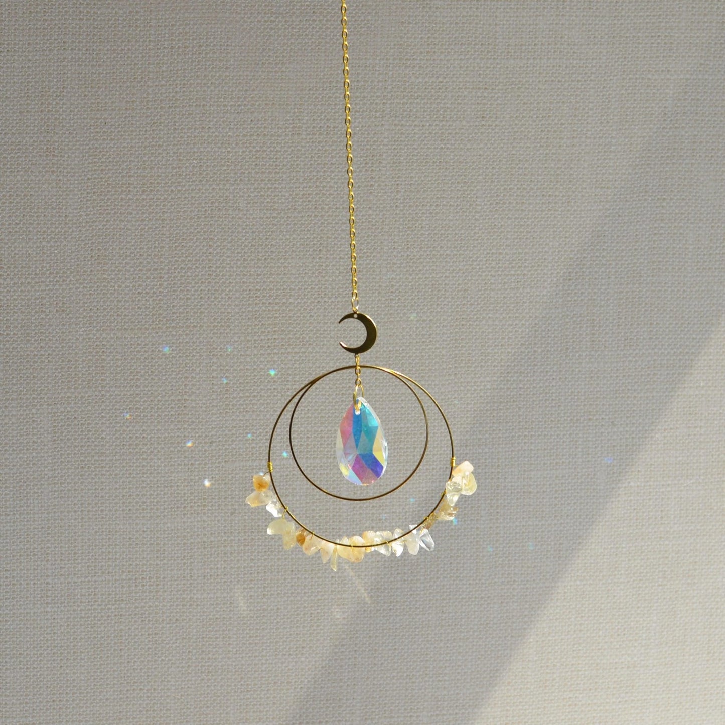 Crescent & Sun Crystal Suncatcher hanging in sunlight casting rainbow prisms.