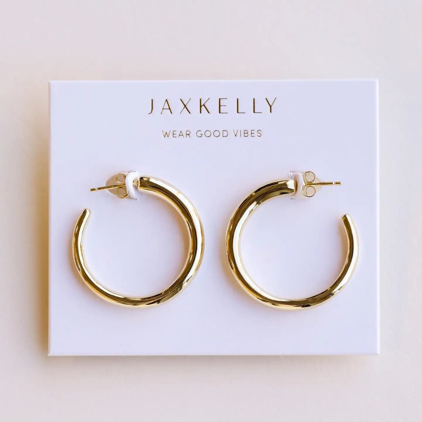 Gold hoop earrings on a Jaxkelly branded card with a beige background