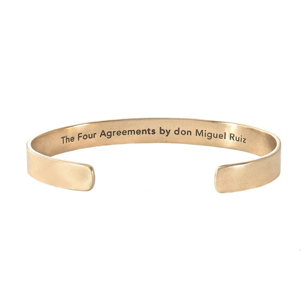 Gold bracelet with 'The Four Agreements by don Miguel Ruiz' text on a white background