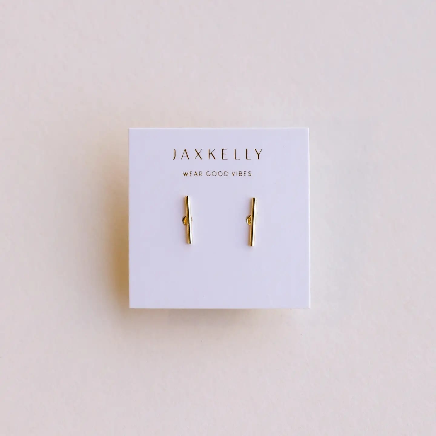Gold bar earrings on a Jaxkelly branded card against a beige background