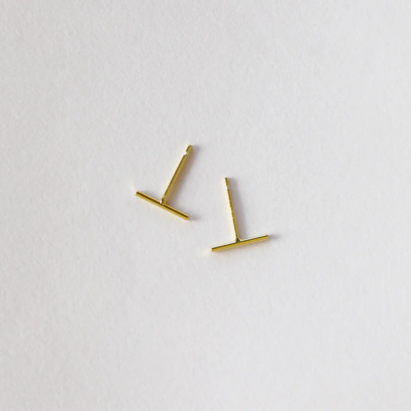 Gold bar earrings on a light gray background