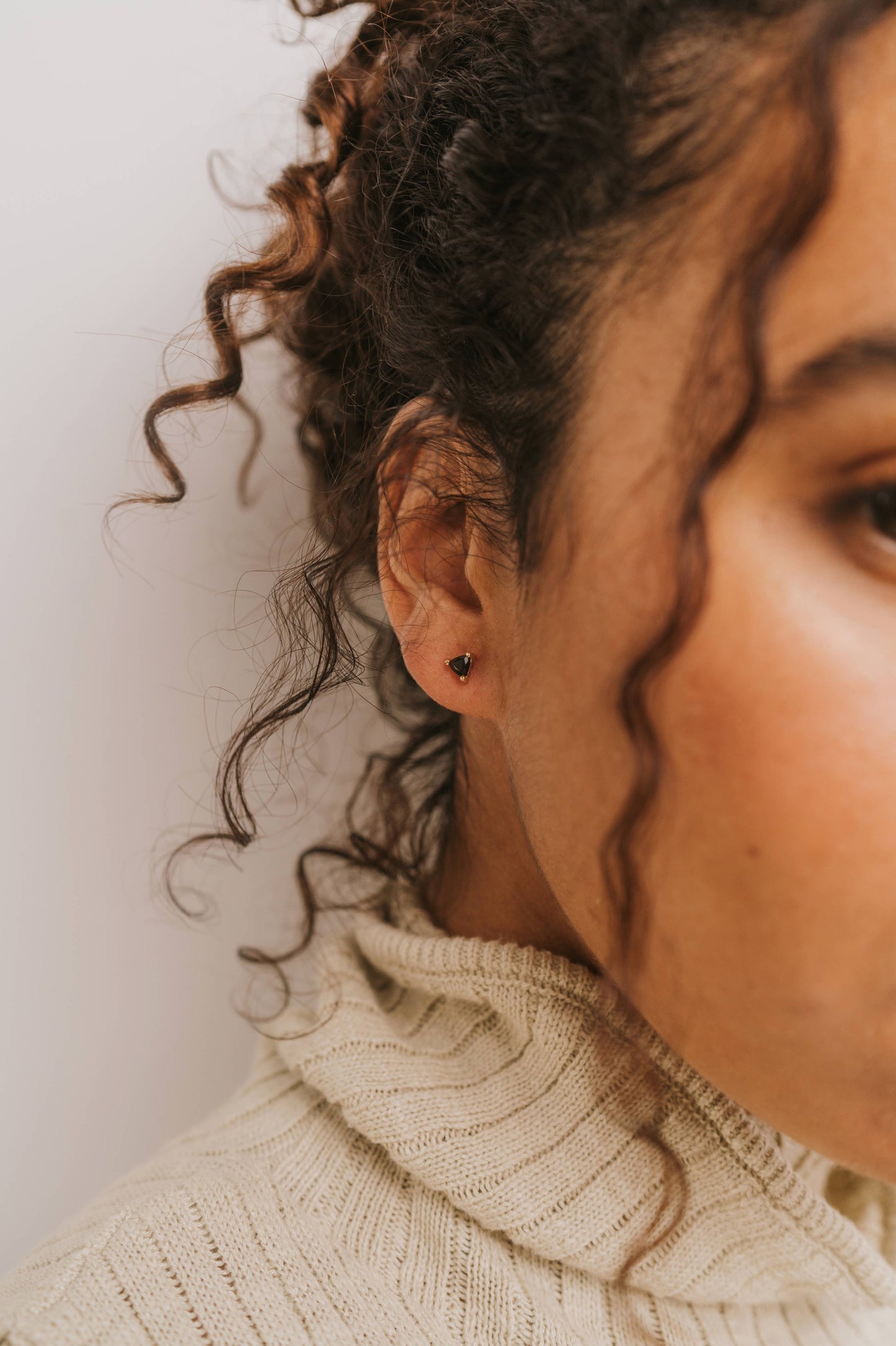 Close-up of a person wearing an earring with a neutral background