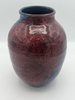 Ceramic vase with a speckled red glaze on a white background