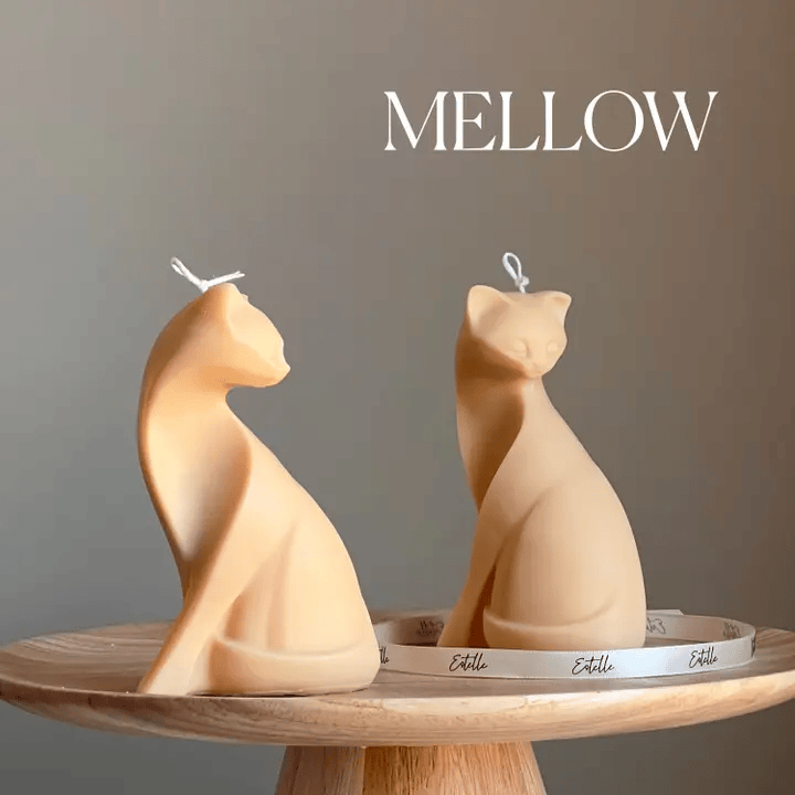 Two cat-shaped candles on a wooden stand with 'Mellow' text above.