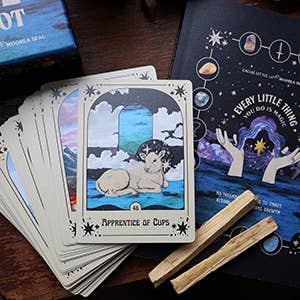 Tarot cards with a wolf card and a book titled 'Every Little Thing You Do Matters' on a wooden surface.