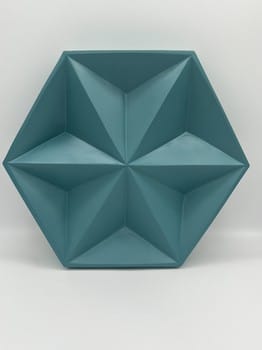 Geometric teal wall art with a star-like design on a white background