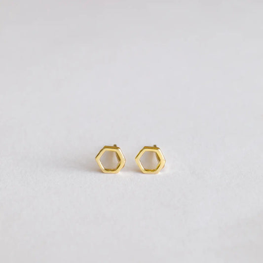 Gold hexagonal stud earrings on a light gray background