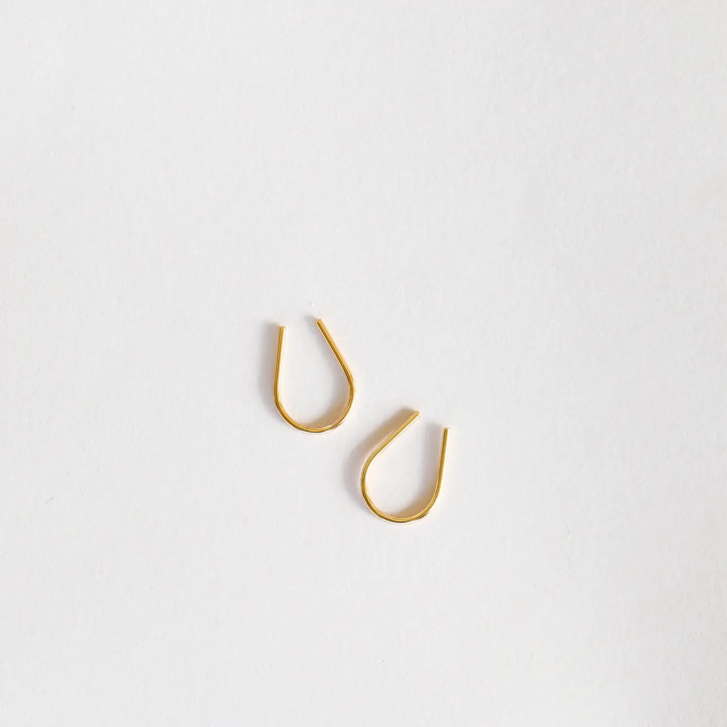 Gold hook earrings on a light gray background