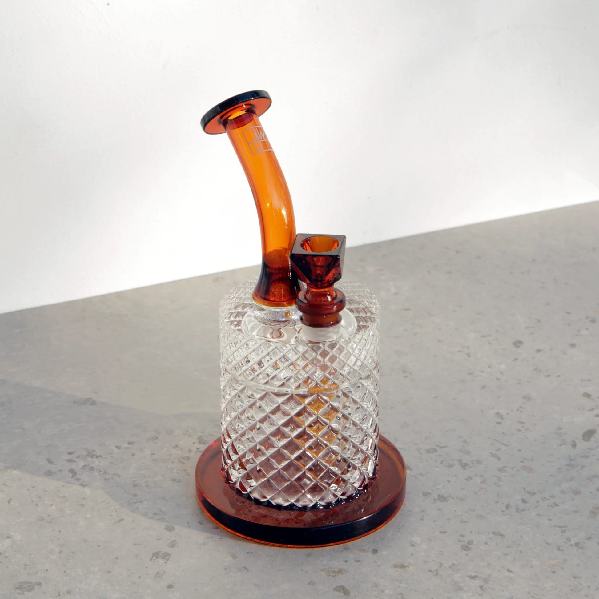 Glass smoking device with amber neck on a gray surface