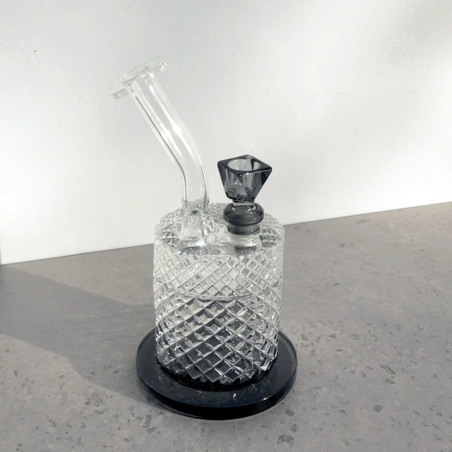 Glass water pipe with diamond pattern on a gray surface