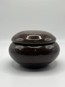 Brown ceramic jar with lid on a white background