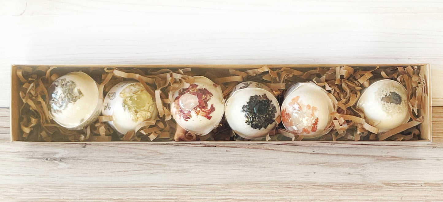 Set of six decorative bath bombs in a wooden box on a light wooden surface.