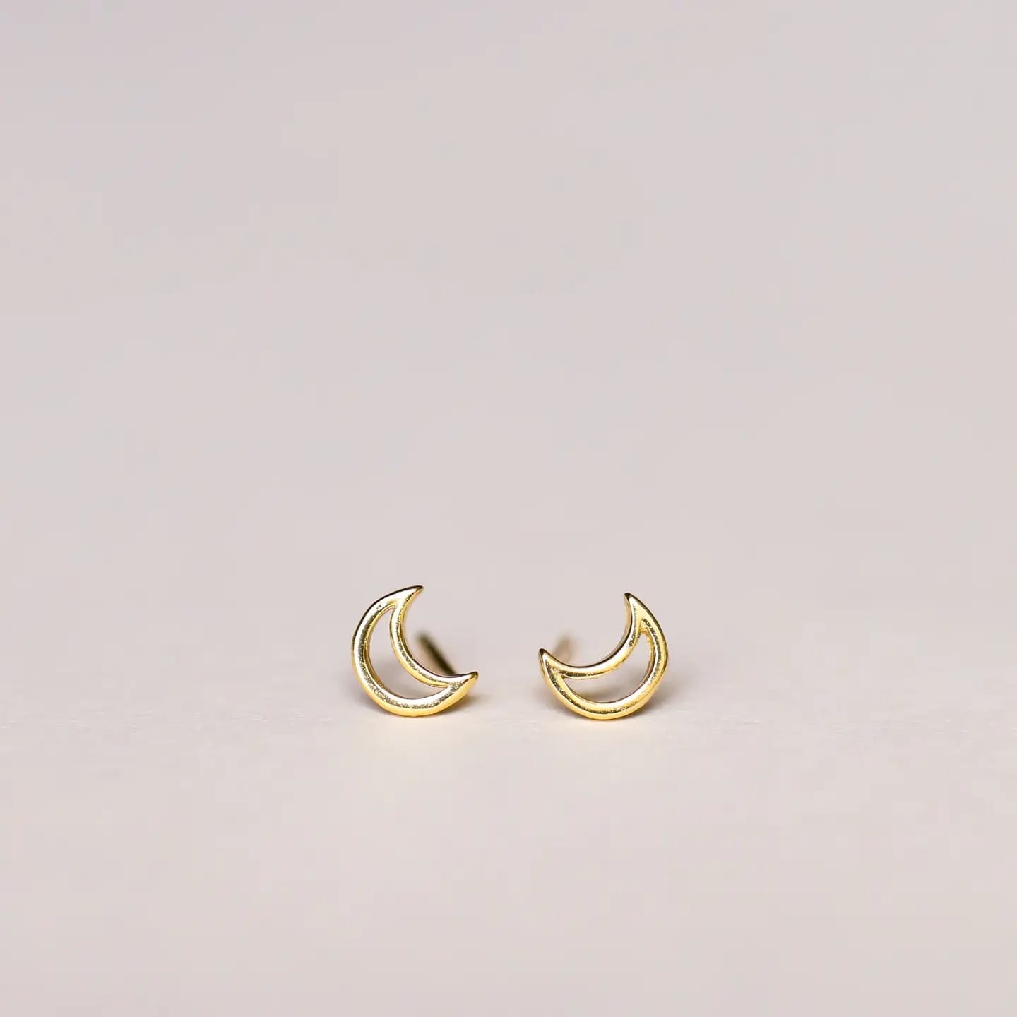 Gold crescent moon earrings on a light gray background