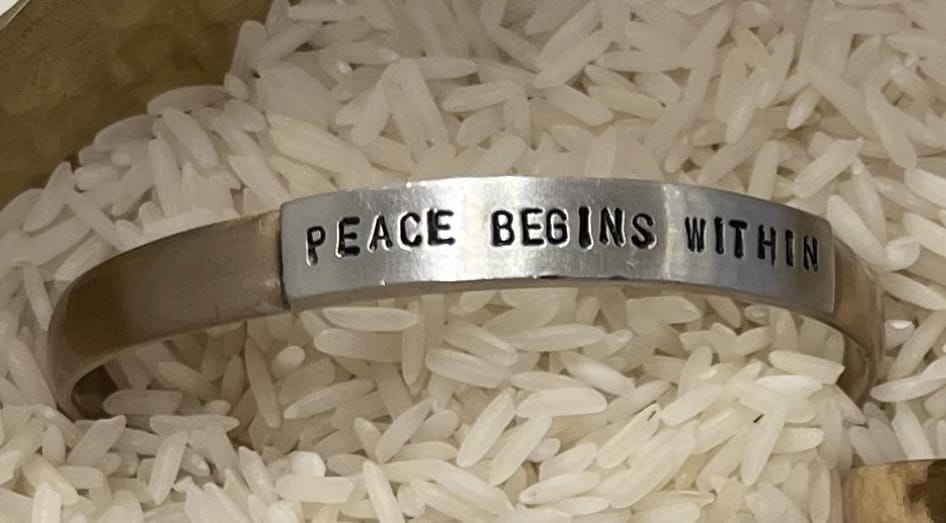 Silver bracelet with 'PEACE BEGINS WITHIN' text