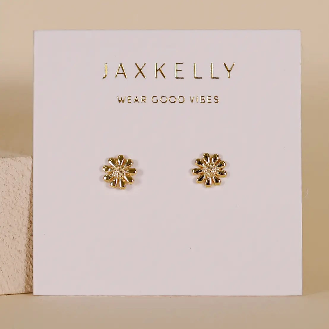 Gold flower-shaped earrings on a Jaxkelly branded card with 'Wear Good Vibes' text.