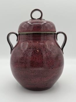Red ceramic jar with a lid on a white background