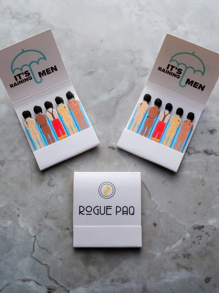 Two matchboxes labeled 'It's Raining Men' and one labeled 'Rogue Paq' 
