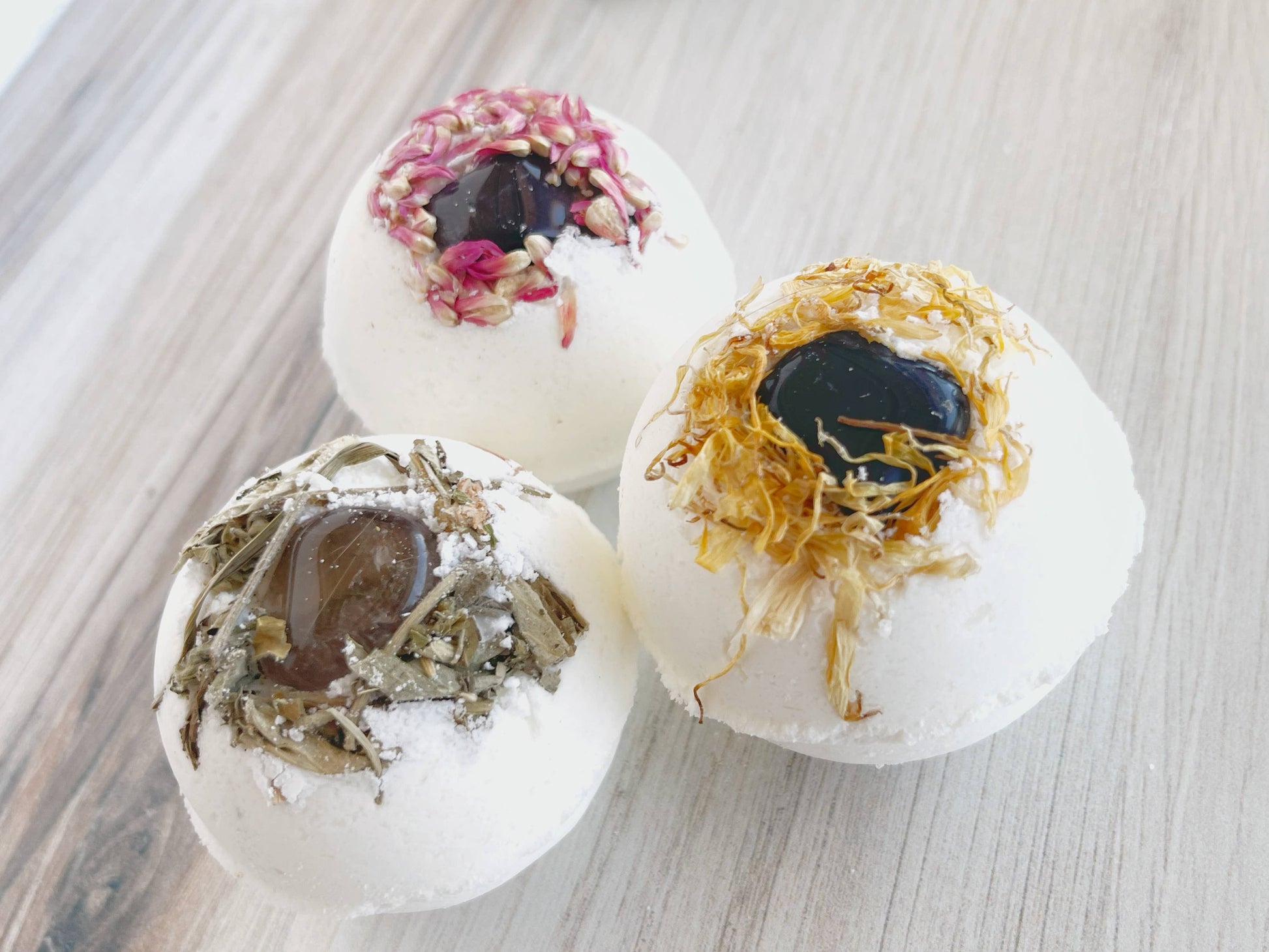 Three bath bombs with natural ingredients on a wooden surface