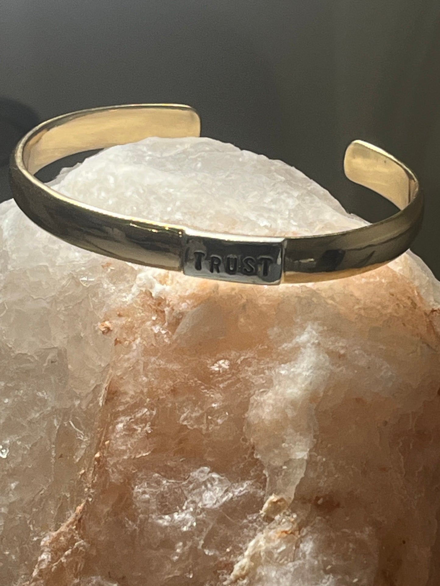 Gold bracelet with 'TRUST' engraving on a crystal surface