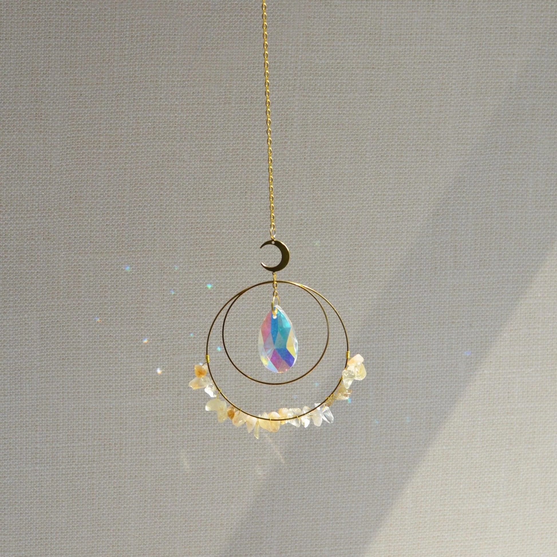 Crescent & Sun Crystal Suncatcher hanging in sunlight casting rainbow prisms.