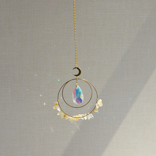 Crescent & Sun Crystal Suncatcher hanging in sunlight casting rainbow prisms.