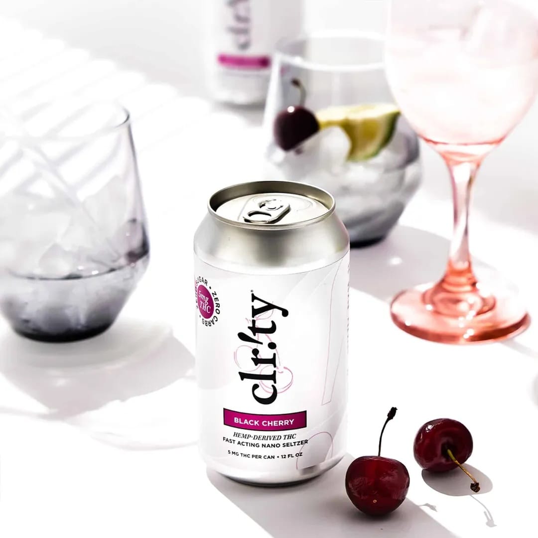 Can of clrty black cherry drink with cherries and glasses in the background
