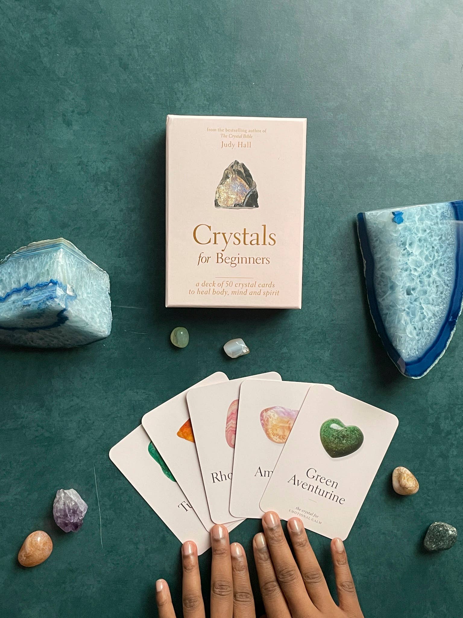 Card game set up with crystals and a book titled 'Crystals for Beginners' on a green surface.