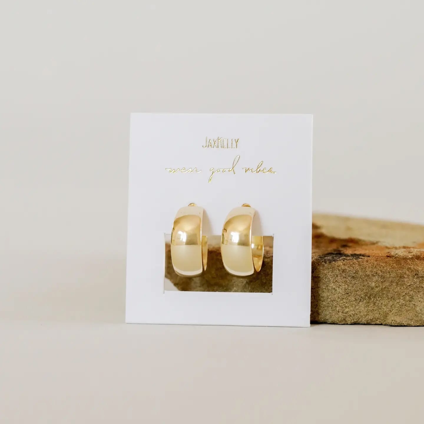 Gold hoop earrings on a white card with 'Jewelry' text, placed on a wooden surface.