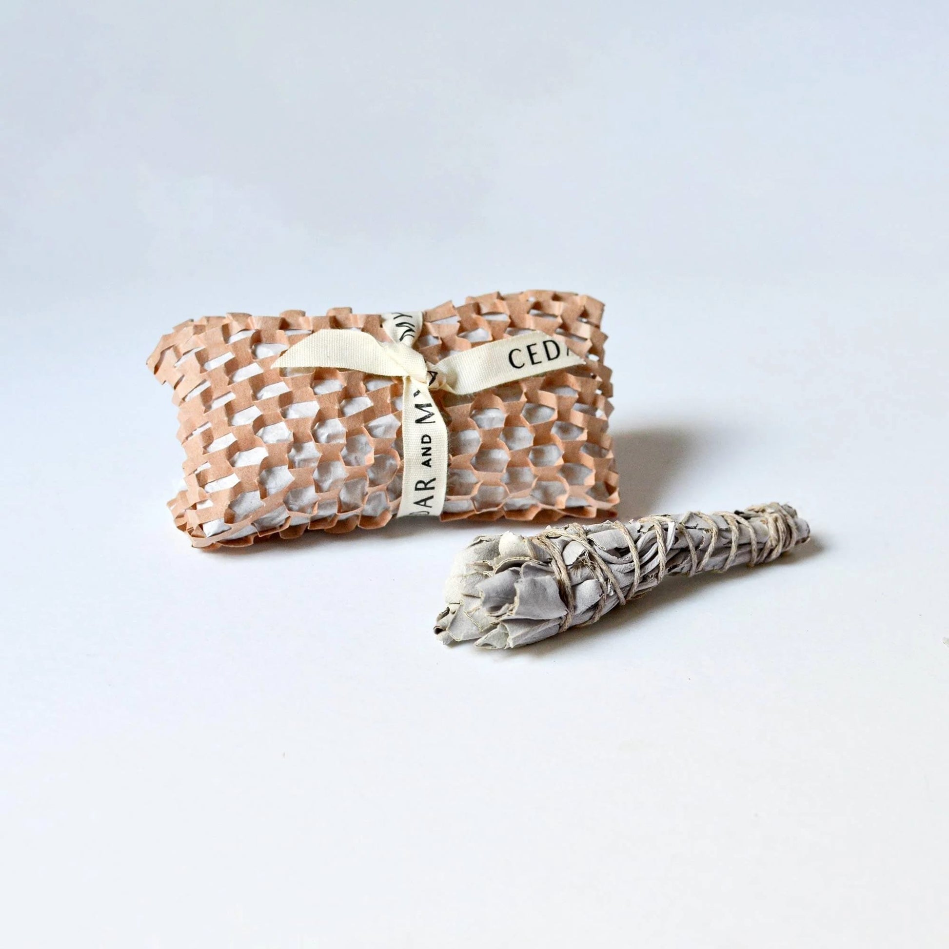 Sage bundle and woven pouch on a light gray background