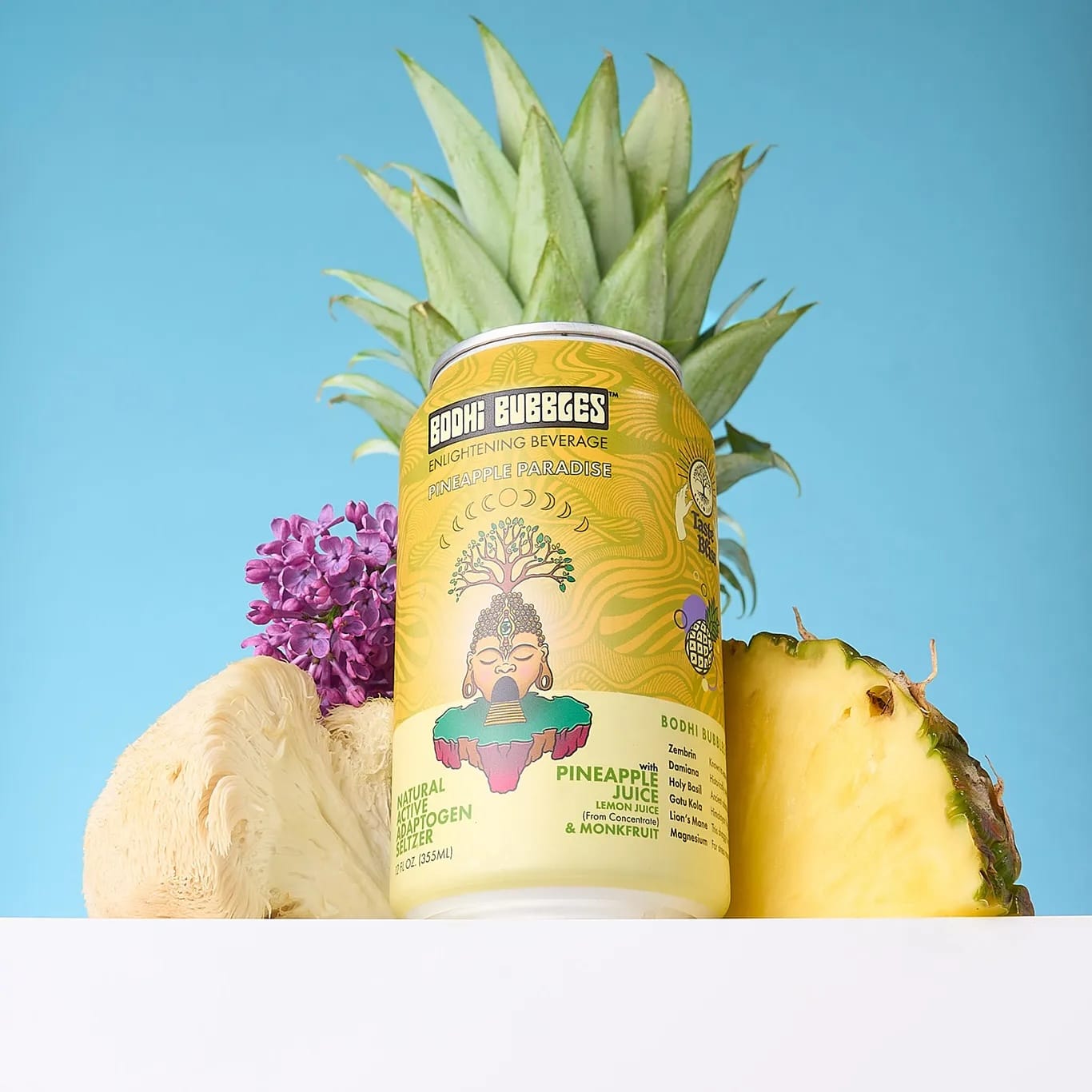 Buddha Beverages pineapple juice can with a pineapple and flowers on a blue background