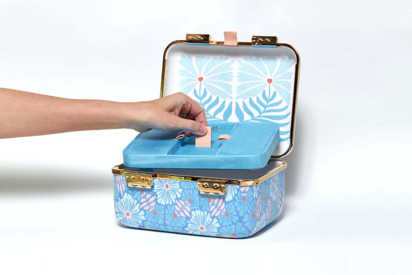 Blue floral-patterned jewelry box with a hand opening it on a white background