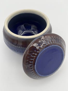 Ceramic container with blue interior and brown exterior on a white background