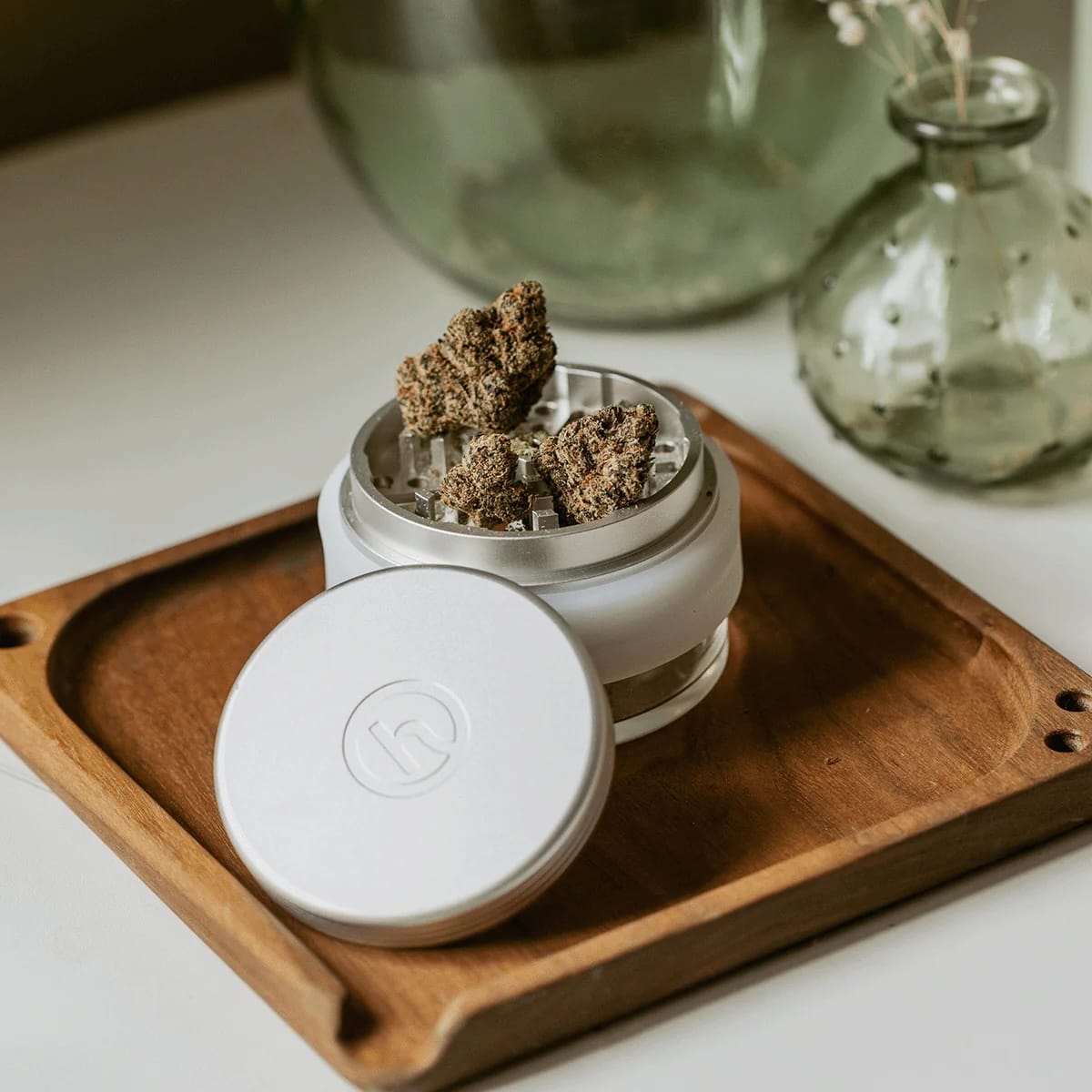 White container with cannabis buds on a wooden tray