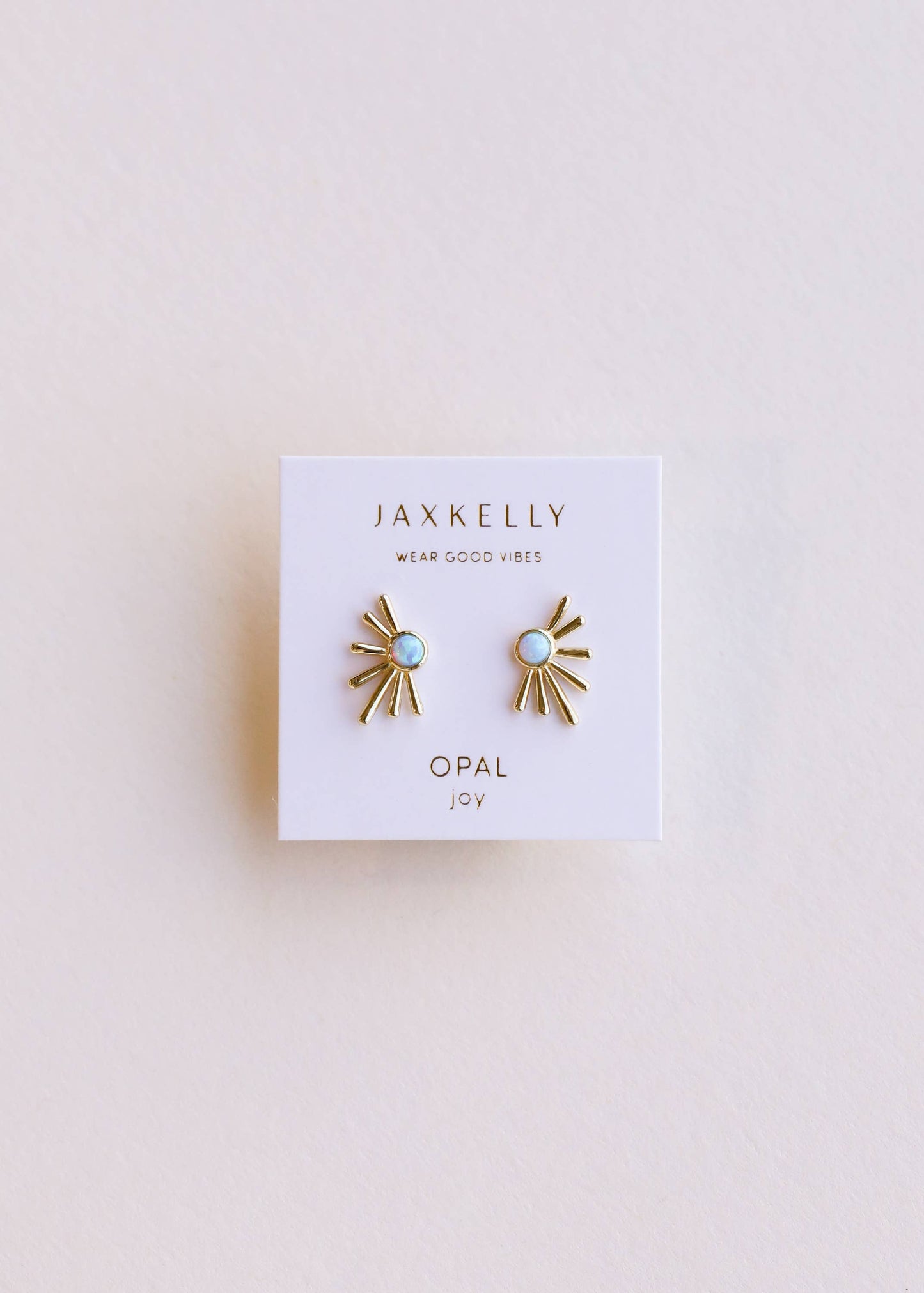 Pair of gold and opal earrings on a Jaxkelly branded card against a light background