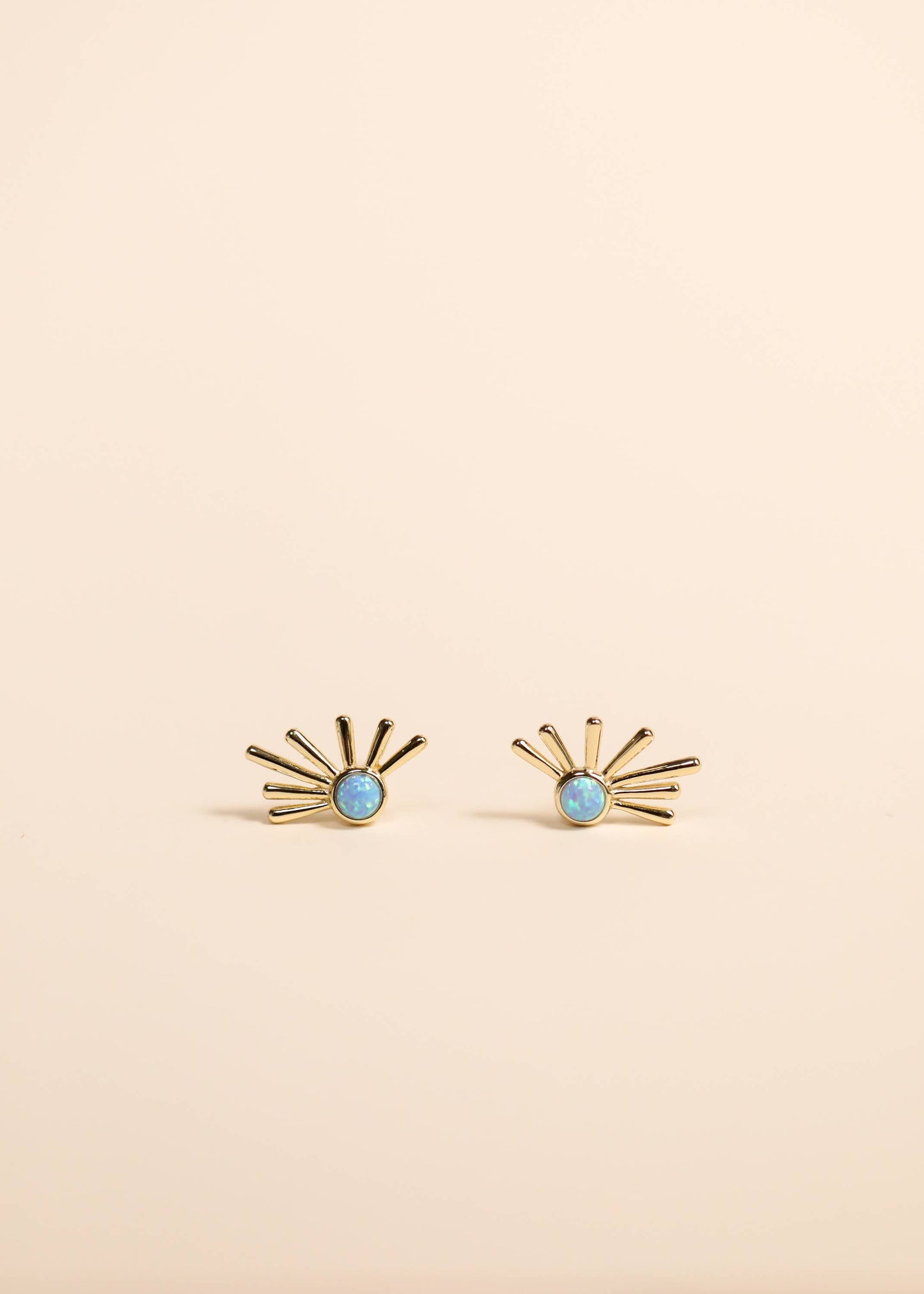 Gold earrings with turquoise stones on a beige background