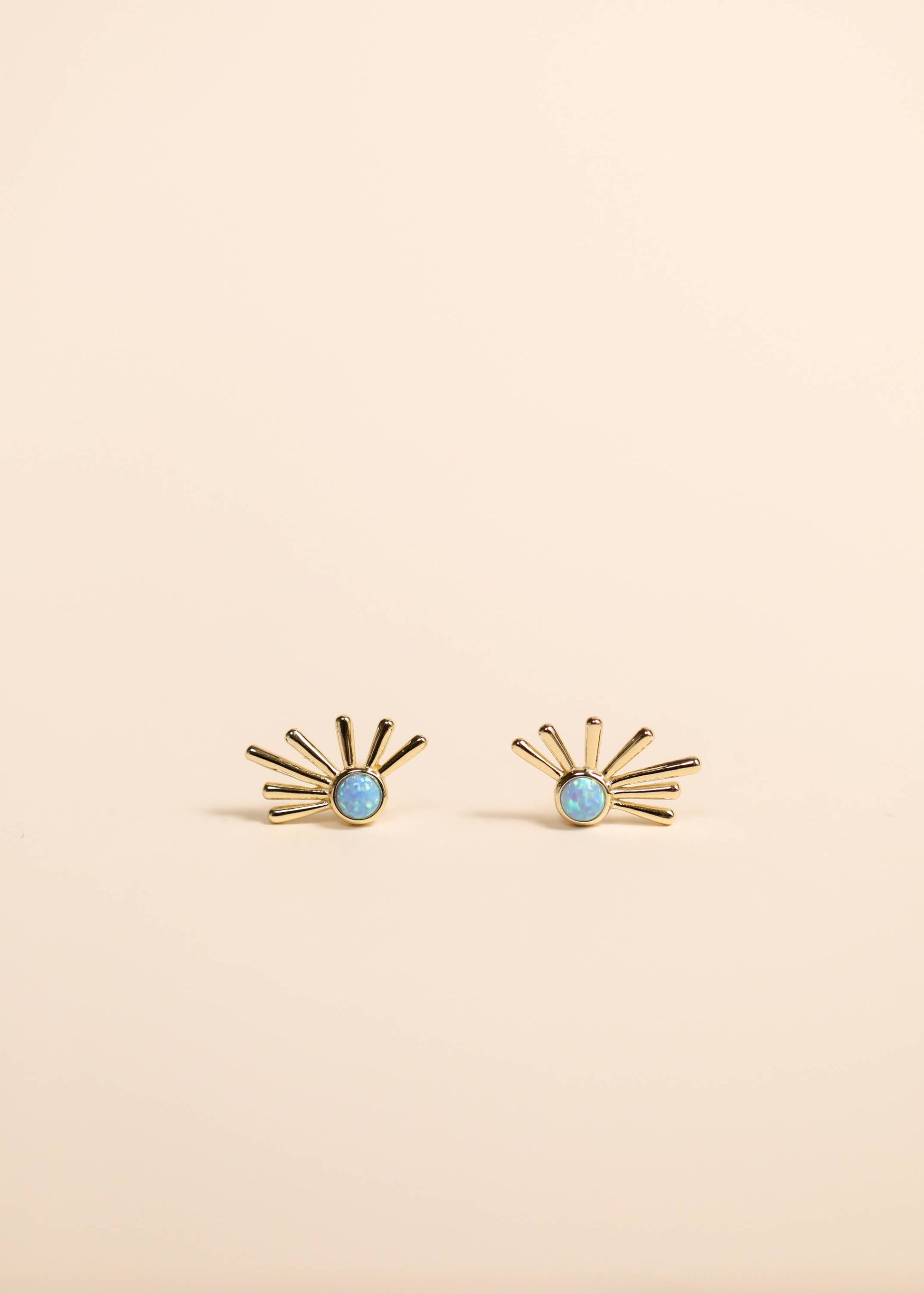 Gold earrings with turquoise stones on a beige background
