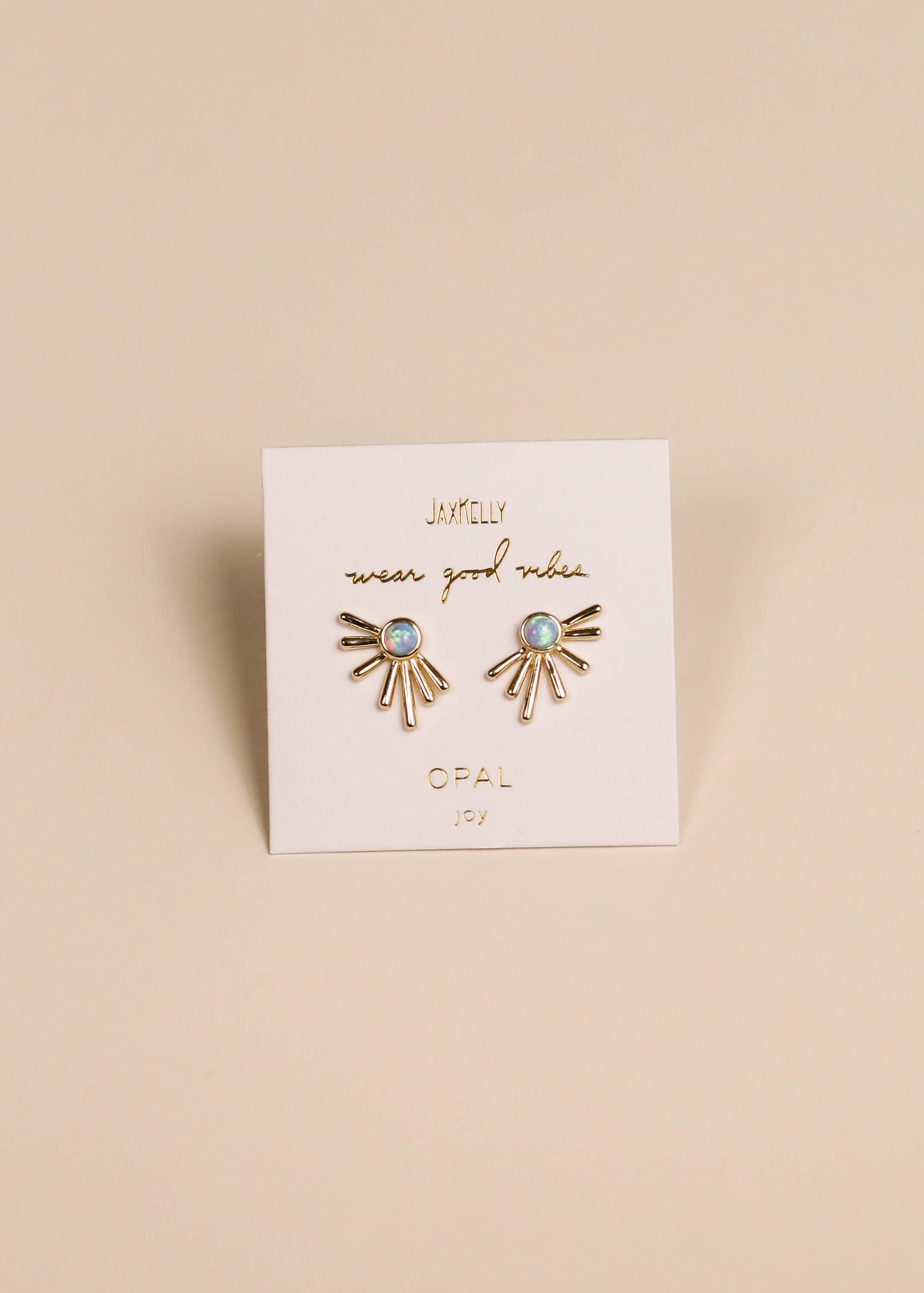 Gold earrings with blue stones on a branded card against a beige background